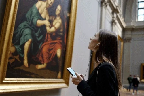 Visitatrice con audioguida davanti a un dipinto agli Uffizi